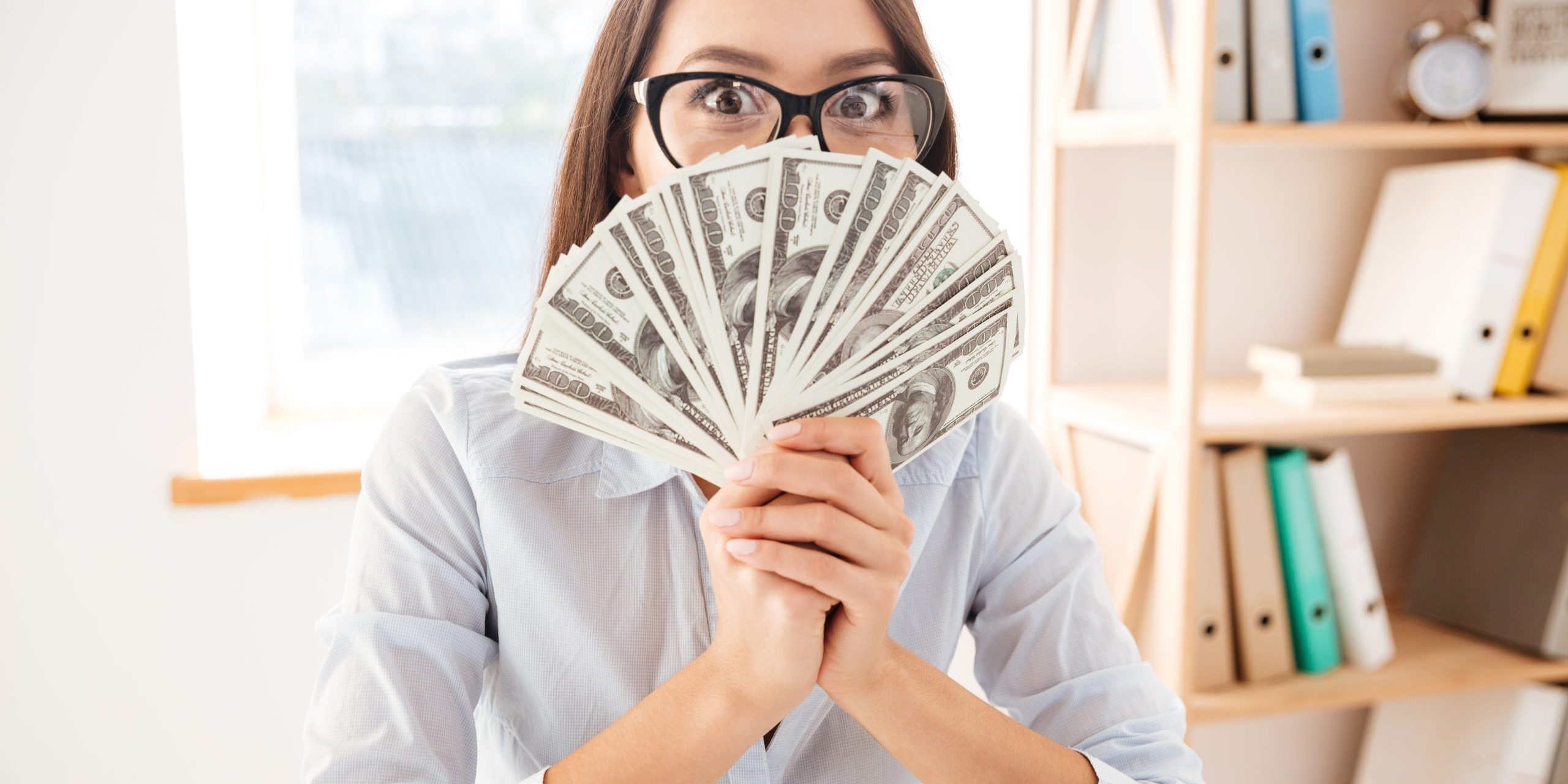 Businesswoman holding money in hand near face